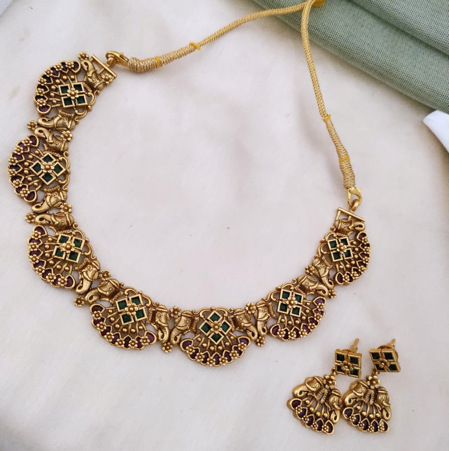 Golden necklace with kemp stones and majestic trunk motif on both sides